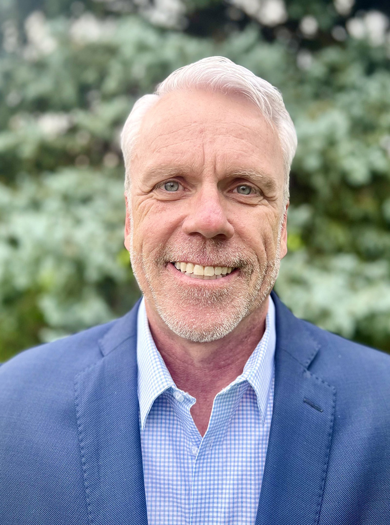 a man wearing a suit and tie smiling at the camera