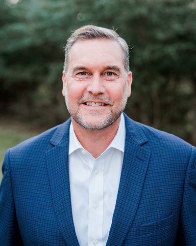 a man wearing a suit and tie smiling at the camera