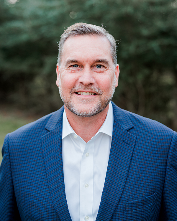 a man wearing a suit and tie smiling at the camera