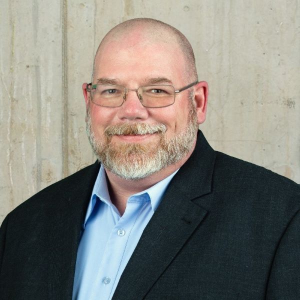 a man wearing a suit and tie smiling at the camera