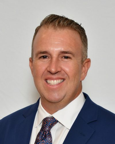 a man wearing a suit and tie smiling at the camera