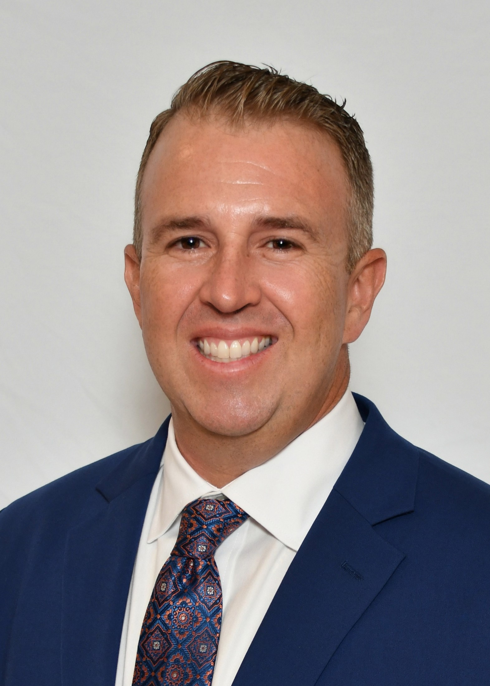a man wearing a suit and tie smiling at the camera