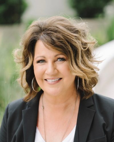a woman wearing a suit and tie smiling at the camera