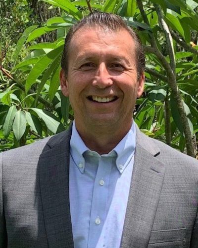a man wearing a suit and tie smiling at the camera