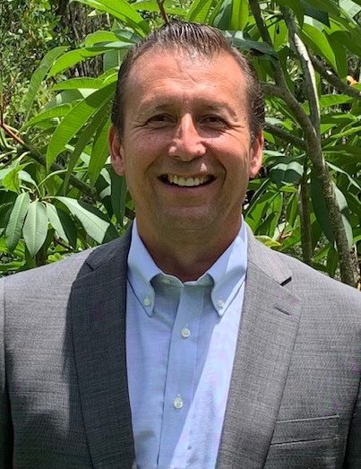 a man wearing a suit and tie smiling at the camera