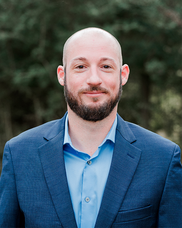 a man wearing a suit and tie smiling at the camera