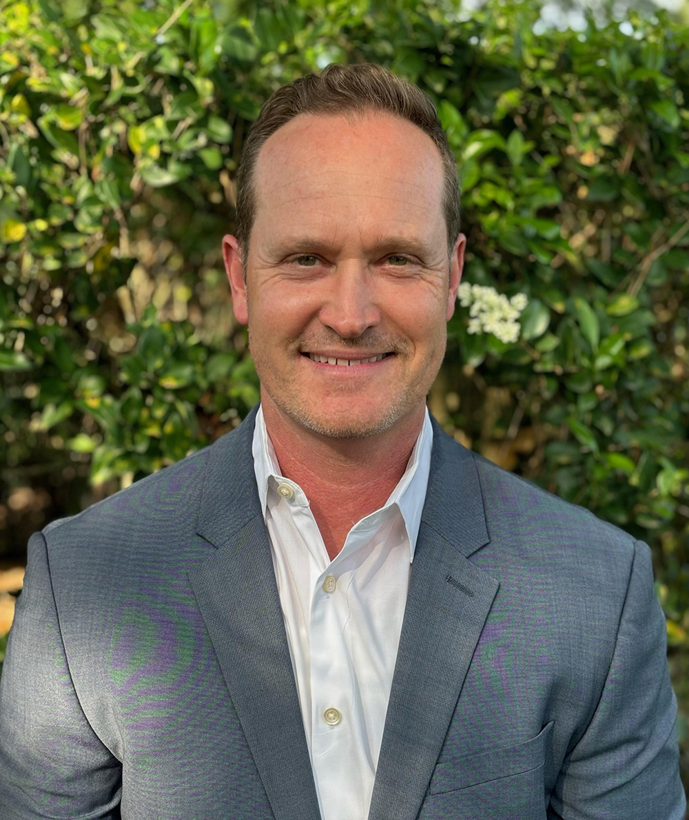 a man wearing a suit and tie smiling at the camera
