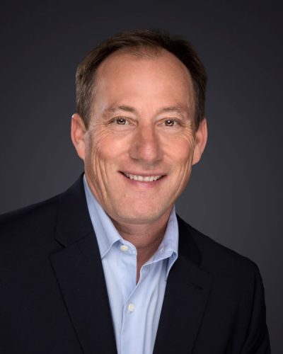 a man wearing a suit and tie smiling at the camera
