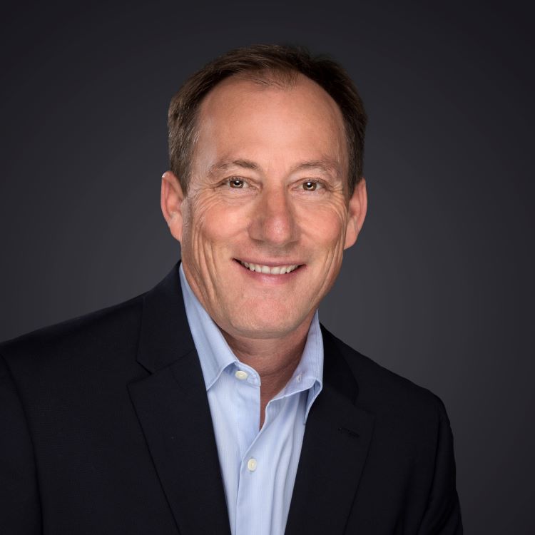 a man wearing a suit and tie smiling at the camera