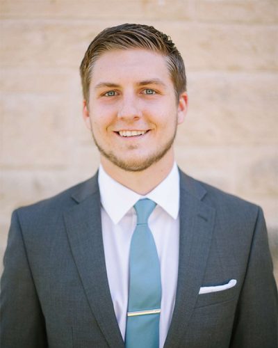 a man wearing a suit and tie smiling at the camera
