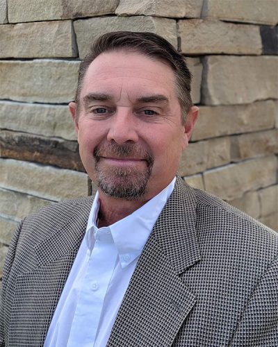 a man wearing a suit and tie smiling at the camera