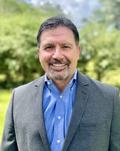 a man wearing a suit and tie smiling at the camera
