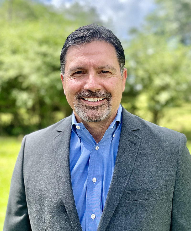 a man wearing a suit and tie smiling at the camera