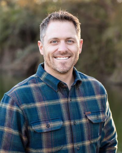 a man wearing a blue shirt and smiling at the camera