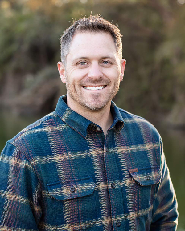 a man wearing a blue shirt and smiling at the camera
